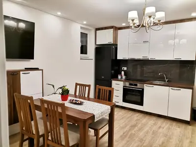 a kitchen with a table and a kitchen with white cabinets at City Break Apartment in Banja Luka