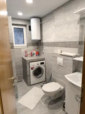a bathroom with a toilet and a washing machine at City Break Apartment in Banja Luka