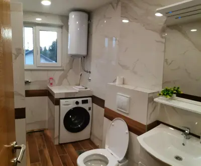 a bathroom with a toilet and a sink and a washing machine at City Break Apartment in Banja Luka