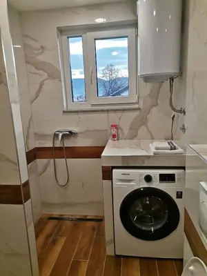 a bathroom with a washing machine and a window at City Break Apartment in Banja Luka