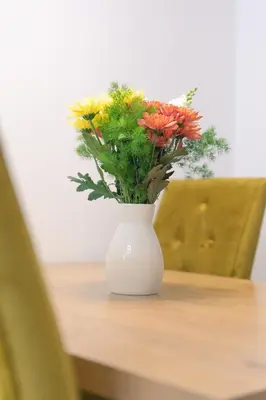a white vase with flowers in it on a table at Drobac apartment in Banja Luka