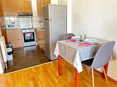 a kitchen with a table and a stainless steel refrigerator at Titanik Tuzla in Tuzla