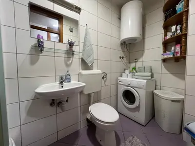 a bathroom with a toilet sink and a washing machine at Titanik Tuzla in Tuzla