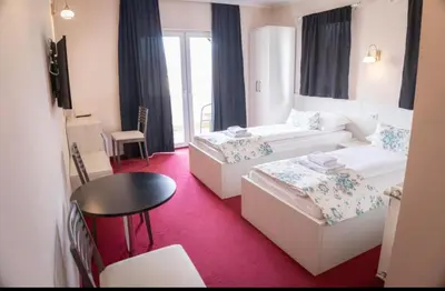 a hotel room with two beds and a table at Apartmani i sobe Centar Bugojno in Bugojno
