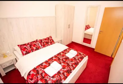a bedroom with a bed with a red blanket and a mirror at Apartmani i sobe Centar Bugojno in Bugojno