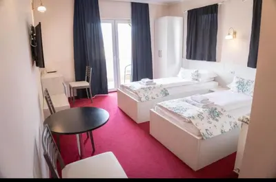 a hotel room with two beds and a table at Apartmani i sobe Centar Bugojno in Bugojno