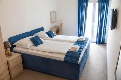 a large bed in a room with blue curtains at Apartmani i sobe Centar Bugojno in Bugojno
