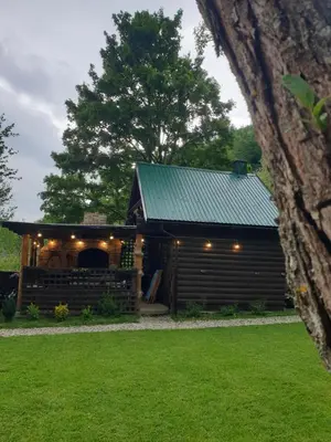 a log cabin with a green roof and lights on it at Jajce lake cottage-Plivsko jezero in Jajce