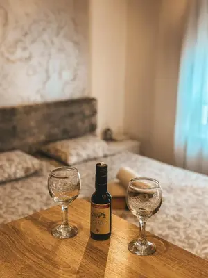 a bottle of wine and two wine glasses on a table at Apartman Vila Bojana in Budžak