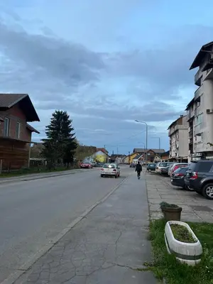 a person walking down a street with cars parked at Apartman MS in Bosanska Dubica
