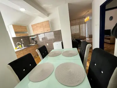 a dining room table with chairs and a kitchen at Apartman MS in Bosanska Dubica