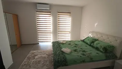 a bedroom with a bed with green sheets and pillows at Grand Apartman in Živinice