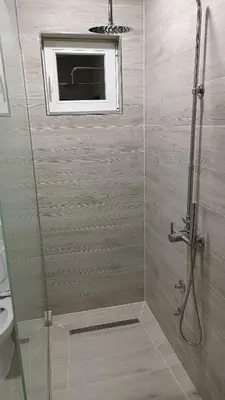 a bathroom with a shower with a window at Grand Apartman in Živinice