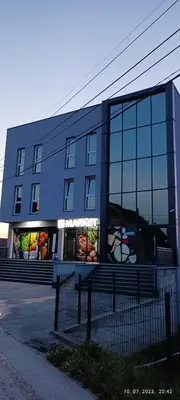 a blue building with glass windows on a street at Grand Apartman in Živinice