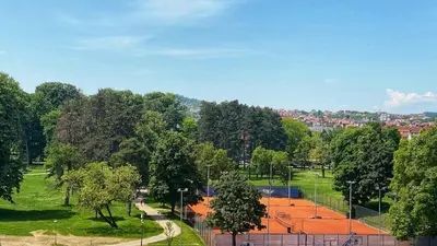 a tennis court in a park with trees at Park & Play in Banja Luka