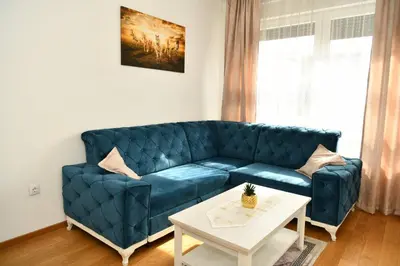 a blue couch in a living room with a table at Apartman Panorama Banja Luka in Banja Luka