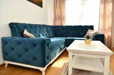 a blue couch in a living room with a table at Apartman Panorama Banja Luka in Banja Luka