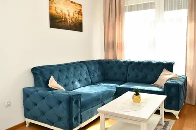 a blue couch in a living room with a table at Apartman Panorama Banja Luka in Banja Luka