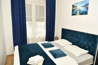 a bedroom with a bed with blue curtains at Apartman Panorama Banja Luka in Banja Luka