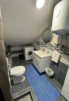 a bathroom with a toilet and a sink and a washing machine at Stan Nova Varos Banjaluka in Banja Luka