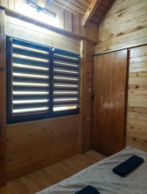 a room with a bed and a window in a log cabin at Hacienda Burzić in Kulen Vakuf