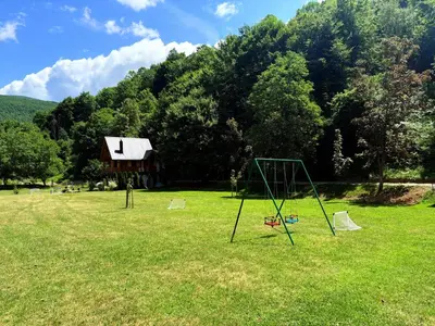 a park with a swing set in the grass at Hacienda Burzić in Kulen Vakuf