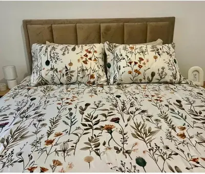 a bed with a floral comforter and two pillows at Skylight studio Banja Luka in Banja Luka