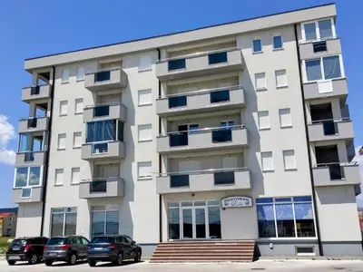 a white building with cars parked in front of it at Apartment Maria in Tomislavgrad