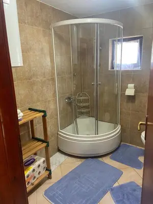 a bathroom with a shower with blue mats in it at Apartman Zeko in Kupres