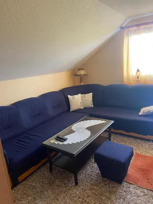 a blue couch in a living room with a table at Apartman Zeko in Kupres