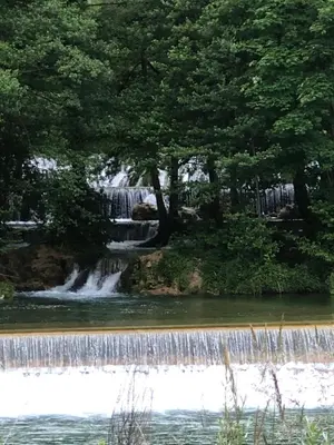 a waterfall in the middle of a river with trees at Graciaa in Jajce