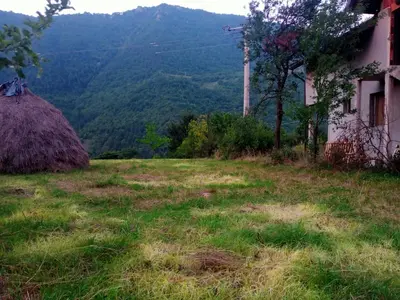 a house in a field with a mountain in the background at Family House بيت عائلي بجميع مواصفات الراحة in Travnik