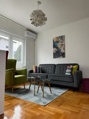 a living room with a black couch and two green chairs at Apartman Green City with garage in Banja Luka