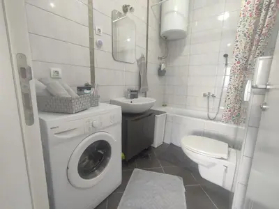 a bathroom with a washing machine and a toilet at Apartman Green City with garage in Banja Luka