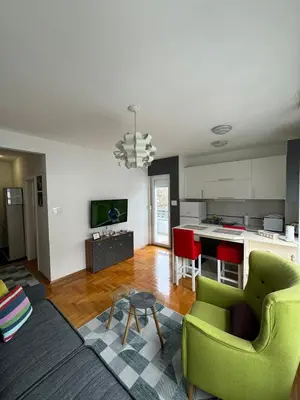 a living room with two green chairs and a kitchen at Apartman Green City with garage in Banja Luka