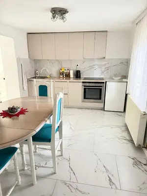a kitchen with white cabinets and a table and chairs at Apartman DIJANA BANJA LUKA in Banja Luka