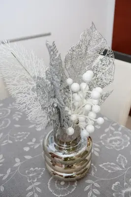 a silver vase with feathers and white balls on a table at Iva Lux stan na dan in Banja Luka