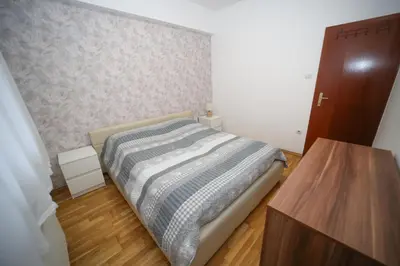 a bedroom with a bed and a wooden table at Iva Lux stan na dan in Banja Luka
