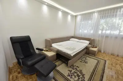 a bedroom with a bed and a chair in a room at Apartman Isidora in Banja Luka
