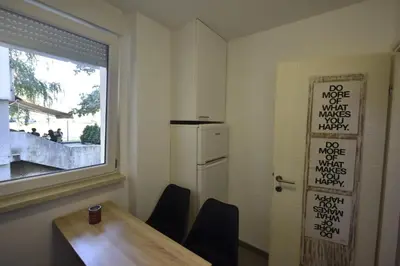 a kitchen with a table and a refrigerator and a window at Apartman Isidora in Banja Luka