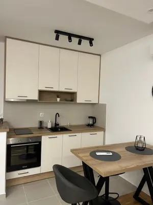 a kitchen with white cabinets and a wooden table at ApartmanM&M in Banja Luka