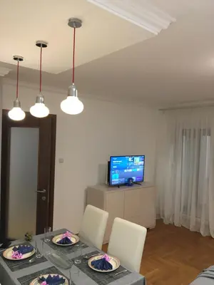 a dining room with a table with chairs and a television at Apartman DeLUX in Banja Luka