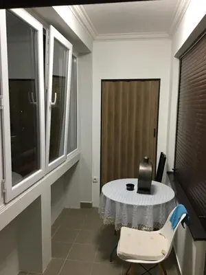a room with a table and a chair and windows at Apartman DeLUX in Banja Luka