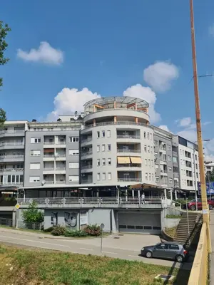 a large white building with a car parked in front of it at Apartman Mirjana in Banja Luka