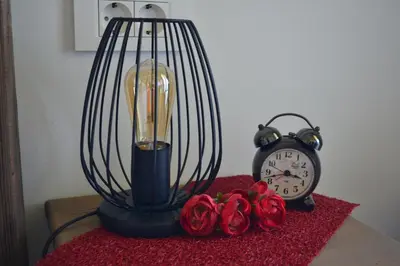 a lamp and a clock on a table with roses at House Na Starom Kućištu in Todorovo