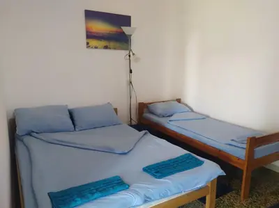 two beds in a room with blue sheets at Apartmani Nova Topola in Nova Topola