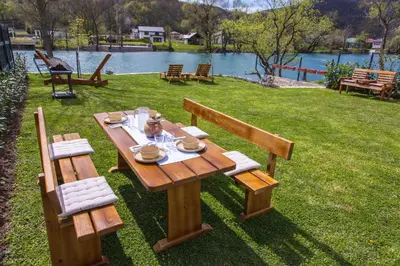 a picnic table in the grass next to a lake at House De Luxe in Bihać
