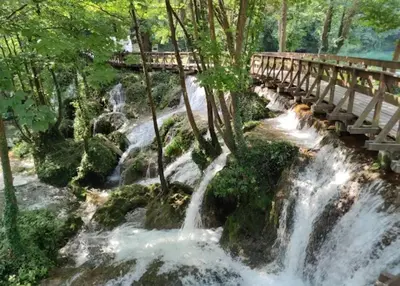 a river with a bridge over a waterfall at Apartman D&D 1 in Jajce