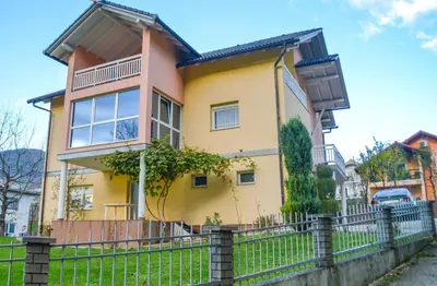 a yellow house with a fence in front of it at Apartman D&D 2 in Jajce