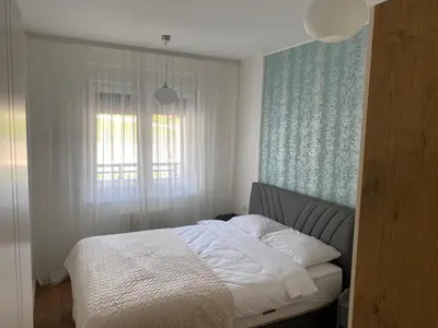 a bedroom with a bed with white sheets and a window at Zeus Apartment in Banja Luka